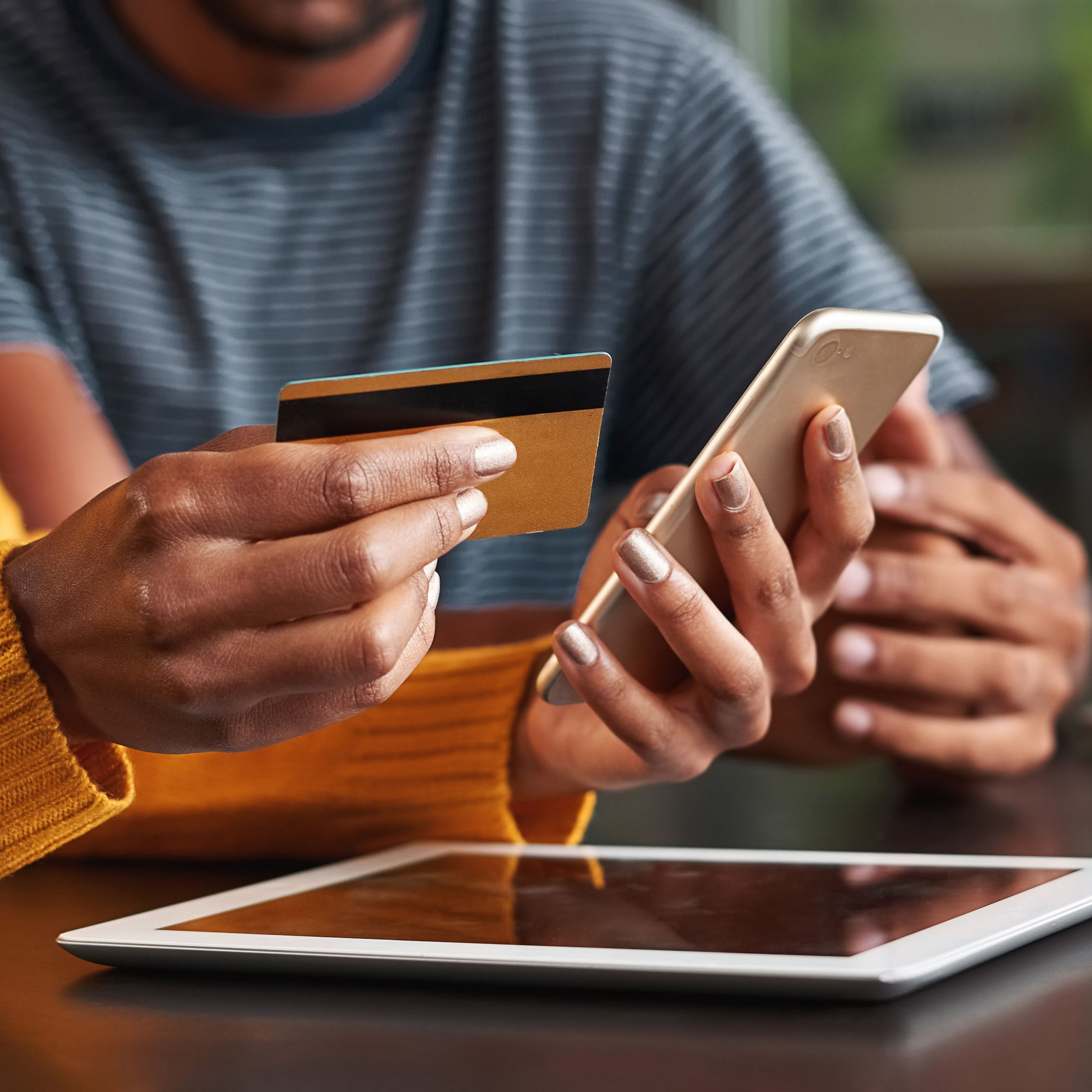 Woman in café holding credit card and mobile phone